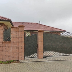 Forged gates and a full fence in modern design with sheet metal ensuring privacy