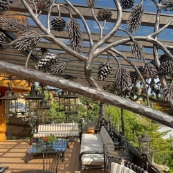 Luxuriöse handgefertigte Terrasse mit naturinspiriertem Design, ausgestattet mit geschmiedeten Möbeln und Beleuchtung Luxuriöse handgefertigte Terrasse mit naturinspiriertem Design, ausgestattet mit geschmiedeten Möbeln und Beleuchtung