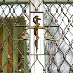 Geschmiedete Waage als Symbol der Pharmazie in einem Fenstergitter  Detailansicht